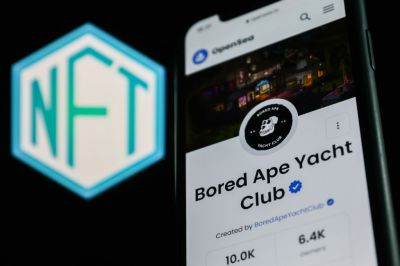 The Bored Ape Yacht Club collection on OpenSea displayed on a phone screen and the NFT logo displayed on a screen are seen in this illustrative photo taken in Krakow, Poland on April 19, 2022. (Photo by Jakub Porzycki/NurPhoto via Getty Images )