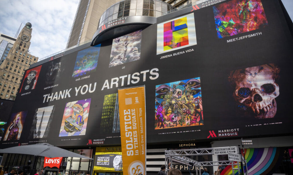 NEW YORK, NEW YORK - JUNE 21: People gather around to watch billboards light up with NFTs as part of the NFT.NYC Conference in Times Square on June 21, 2022 in New York City. Various artists displayed their artwork/ NFTs as part of NFTs minted with NFTKred. (Photo by Alexi Rosenfeld/Getty Images)