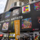 NEW YORK, NEW YORK - JUNE 21: People gather around to watch billboards light up with NFTs as part of the NFT.NYC Conference in Times Square on June 21, 2022 in New York City. Various artists displayed their artwork/ NFTs as part of NFTs minted with NFTKred. (Photo by Alexi Rosenfeld/Getty Images)