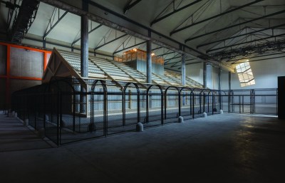 A winding cage that resembles a roller coaster line houses a prefabricated barn from the inside out.